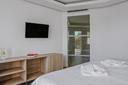 a bedroom with a bed and a tv on a wall at Almyra Resort in Koutsounari