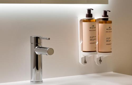 two bottles ofodorizers are on a wall next to a sink at Mercure Montpellier Centre Antigone in Montpellier