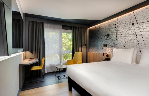 a hotel room with a bed and a desk and a window at Mercure Montpellier Centre Antigone in Montpellier
