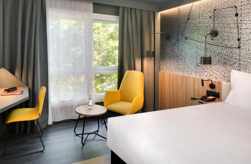 a hotel room with a bed and chairs and a window at Mercure Montpellier Centre Antigone in Montpellier