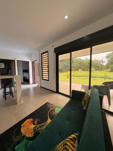 a living room with a green couch and a large window at Tycoon in Matoury