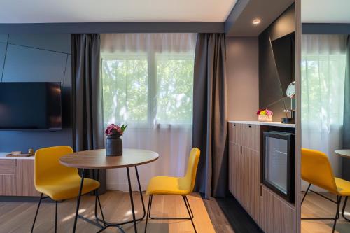 a dining room with a table and yellow chairs at Mercure Montpellier Centre Antigone in Montpellier