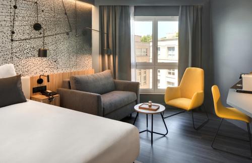a hotel room with a bed and chairs and a window at Mercure Montpellier Centre Antigone in Montpellier