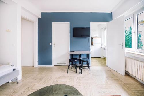 een woonkamer met een blauwe muur en twee krukken bij Studio in City Centre Lux in Luxemburg
