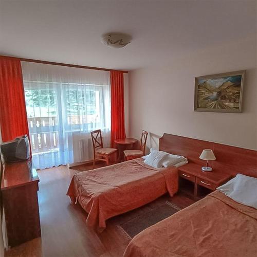 a hotel room with two beds and a television at Ośrodek Wypoczynkowy "Przy Lesie" in Karpacz