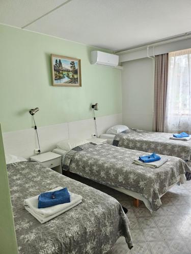 a hotel room with three beds with blue towels on them at Asikkalan Motelli in Vesivehmaa