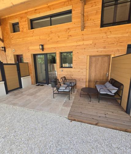 a patio with chairs and tables in front of a wooden building at Gites des ammonites 2 in Montalieu-Vercieu