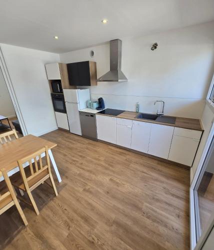a kitchen with white cabinets and a wooden table at Gites des ammonites 2 in Montalieu-Vercieu