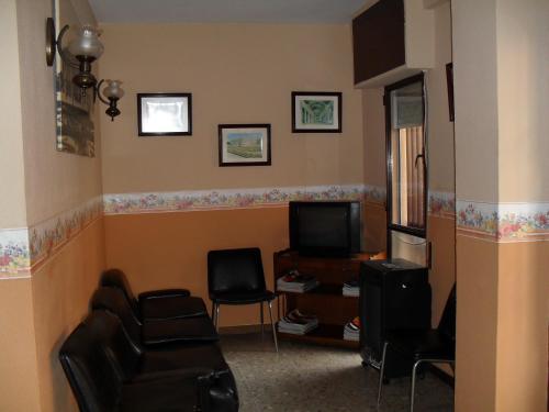 a living room with a couch and chairs and a tv at Pensión Versalles in Algeciras