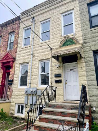 a stone house with a white door and stairs at Cozy 2BR Brick Haven! Near light rail! 35m to NYC in Jersey City