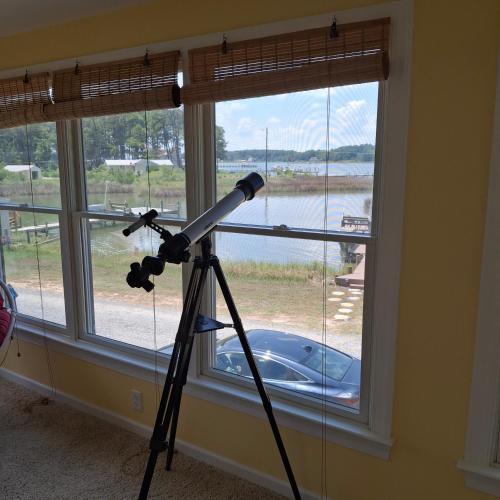 a telescope on a tripod in front of a window at Little Oyster Oasis in White Stone