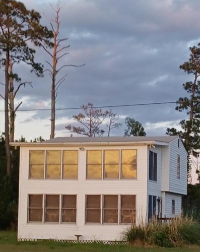 a white house with large windows and trees at Little Oyster Oasis in White Stone