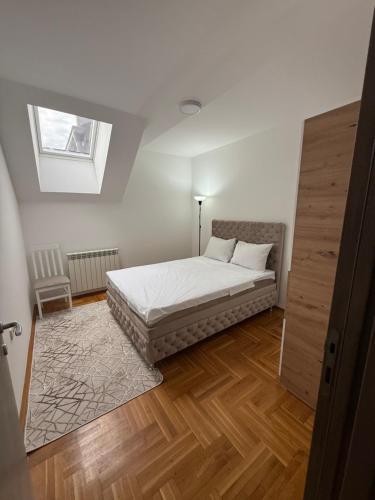 a bedroom with a bed with white sheets and a window at Port 5 in Kalugjerica