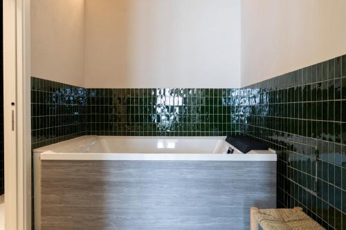 a bath tub in a bathroom with green tiles at I Giardini di Cattaro - History & Comfort in Bari