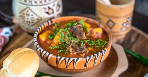 a bowl of soup on a wooden table at Hanul Ceaunelor Voronet in Voronet