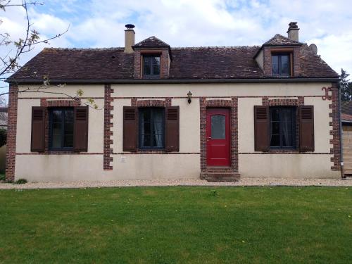 une maison ancienne avec une porte rouge et une cour dans l'établissement Longère au calme en ville, à Senonches