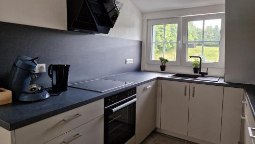 a kitchen with white cabinets and a black counter top at Rosenberghof in Hillesheim