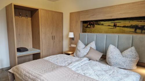 a bedroom with a bed with pillows and a painting at Rosenberghof in Hillesheim