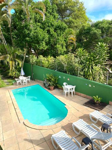 a swimming pool with lounge chairs and a fence at Pousada Arraial Lua Crescente in Arraial d'Ajuda