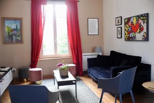 a living room with a black couch and red curtains at Appartements de Diane - JOIGNY in Joigny