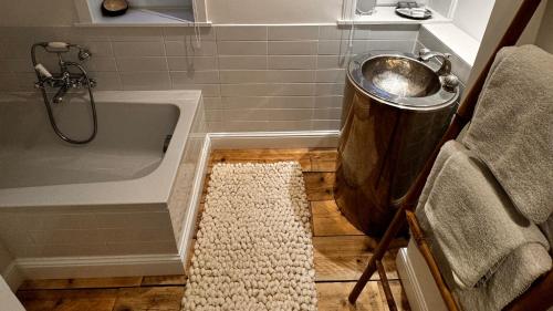 a bathroom with a tub and a trash can next to a rug at Hotel Villa Verdi in Knokke-Heist