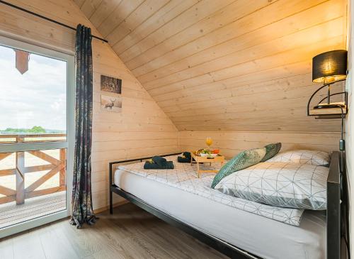 a bed in a wooden room with a window at Domki w Blasku Słońca in Polańczyk