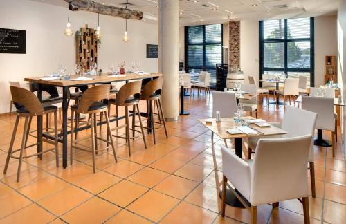 a dining room with tables and chairs and windows at Mercure Montpellier Centre Antigone in Montpellier