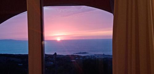 a view of a sunset through a window at LA FRISAIA Appartamento vista mare L4 in Isola Rossa