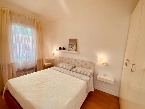 a bedroom with a white bed and a window at LA FRISAIA Appartamento vista mare L4 in Isola Rossa