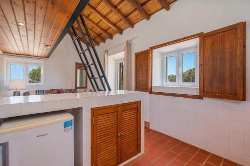 een grote keuken met witte aanrechtbladen en ramen bij Casa da Lua in Aljezur