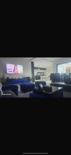 a living room with blue couches and a flat screen tv at Villa Solara in Kelibia