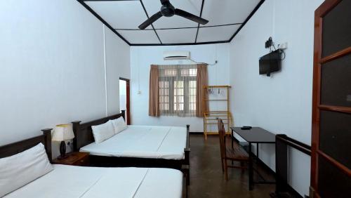 a room with two beds and a table and a window at Old Park Villa in Jaffna