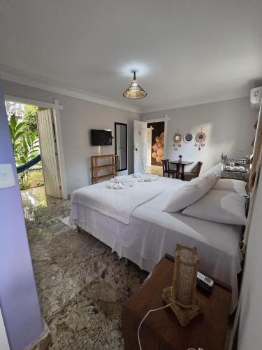 a bedroom with a large white bed and a table at Pousada Blue Ocean in Itacaré
