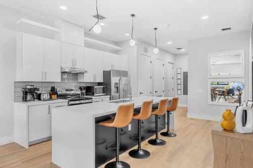 a kitchen with white cabinets and a bar with stools at Wave Haven Suites - 4BR-5BA Luxury - 2 Suites - Walk to Beach - Views in Cocoa Beach