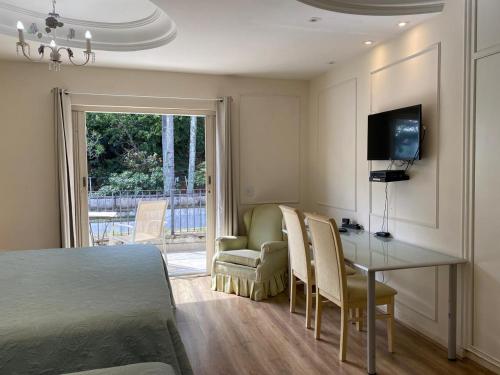 a bedroom with a table and chairs and a television at Suíte no Jardim Guedala in Sao Paulo