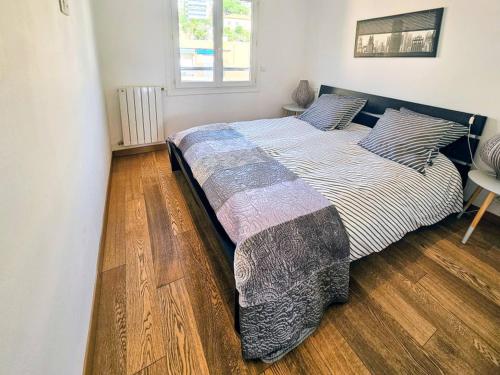 Un dormitorio con una cama grande con suelo de madera. en Beau 2 pieces avec vue imprenable sur la rade, en Villefranche-sur-Mer