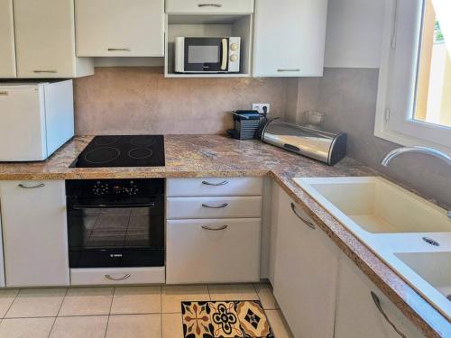 una cocina con estufa horno superior al lado de un fregadero en Beau 2 pieces avec vue imprenable sur la rade, en Villefranche-sur-Mer