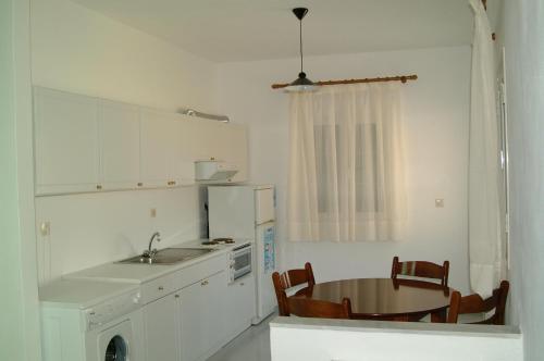 a kitchen with a table and a sink and a refrigerator at Steve Apartments in Áno Garoúna