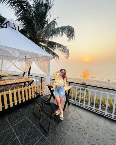 a woman standing at a table near the beach at THE ARABiAN VIEW in Pālghar
