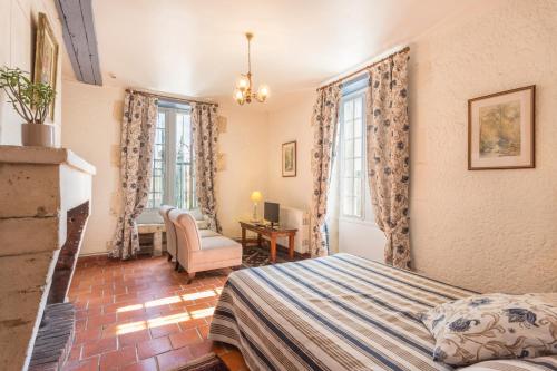 a bedroom with a bed and a chair and windows at Hôtel & SPA Château de La Côte - Brantôme in Biras