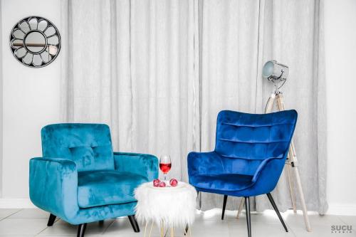 two blue chairs and a table with a glass of wine at The Blyde Crystal lagoon Pretoria in Pretoria