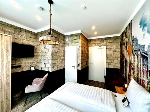 a bedroom with a white bed and a stone wall at Designhotel Central Fulda in Fulda