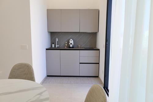 a kitchen with white cabinets and a sink at DR Luxury Apartments in Avola