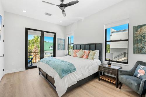 a bedroom with a bed and a chair and windows at Wave Haven Villas - 2 Luxury Villas - 3BR 3 and a Half BA Each - Sleeps 8 Per Unit - Hot Tub - Across from Beach - Rocket and Beach Views in Cocoa Beach