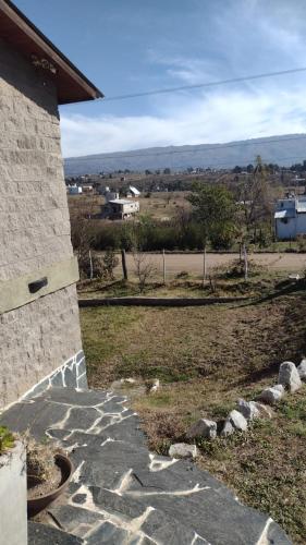 a house with a stone walkway next to a field at El Alma De Yacanto Hotel Boutique in Villa Yacanto
