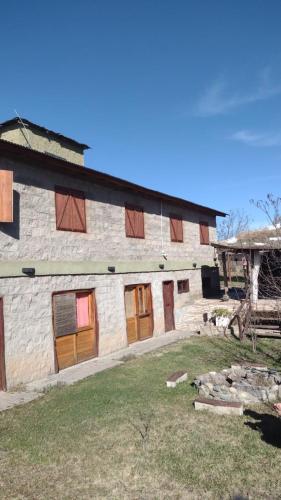 a large stone building with wooden doors on it at El Alma De Yacanto Hotel Boutique in Villa Yacanto