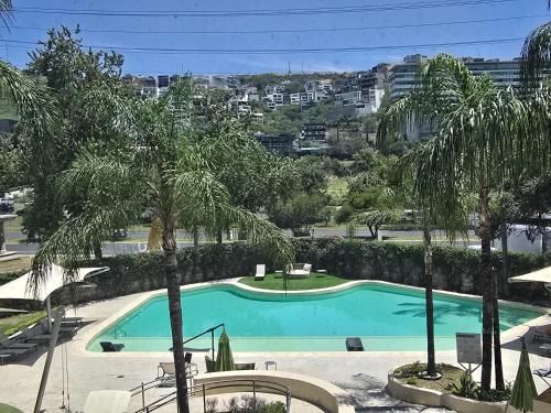 a swimming pool with palm trees in a resort at Novotel Monterrey Valle in Monterrey