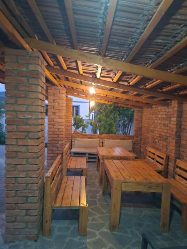 eine Terrasse mit Holztischen und -bänken und einer Ziegelwand in der Unterkunft Red house in Achalziche