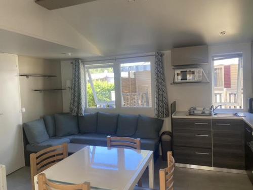 a living room with a blue couch and a table at Mobil Home Casita 6-8 personnes, 3 chambres in Saint-Julien-en-Born