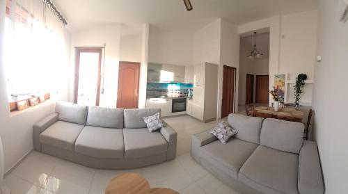 a living room with two couches and a kitchen at Apartament Gabbiano Bianco in Torretta